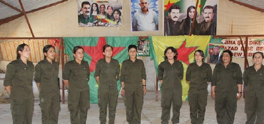 Kurdish women fighters, in Syria, in front of photo of PKK founder Abdullah Ocalan