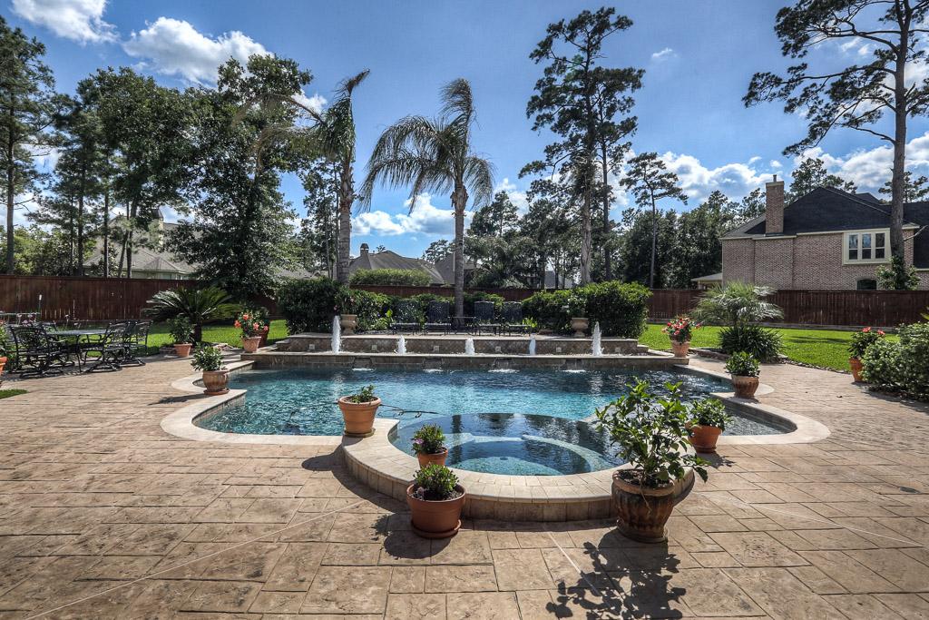 The large backyard features landscaping, a large patio, a pool with fountains and a spa.
