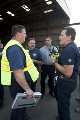 Kimo Kuheana, 92nd Civil Engineer Squadron fire chief, speaks with civilian counterparts on Aug. 12, 2015, after a chemical leak at the Pacific Steel and Recycling plant in Spokane, Wash.