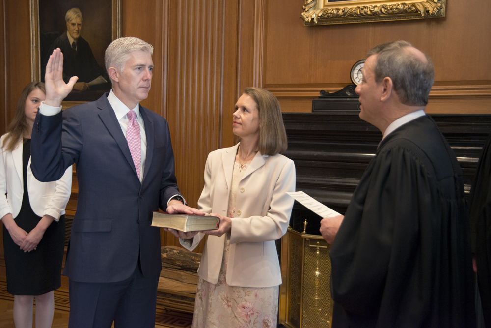Neil Gorsuch (left) is administered the oath of office by Chief Justice John Roberts (right).